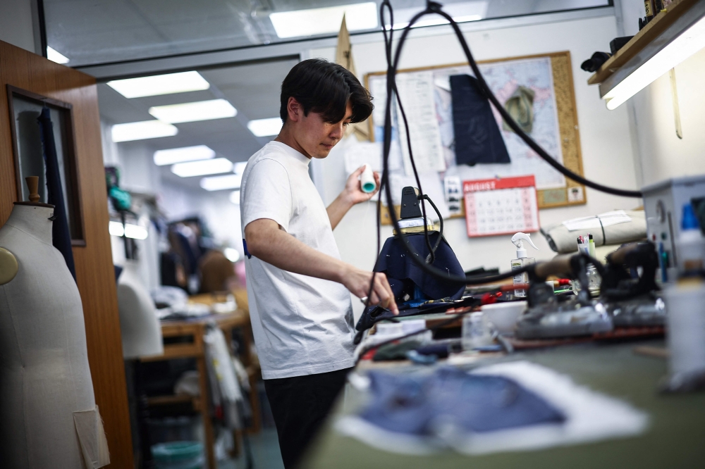 Apprentice tailor George makes adjustments to a waist coat at Henry Poole & Co on Savile Row in London on August 12, 2025. — AFP pic 