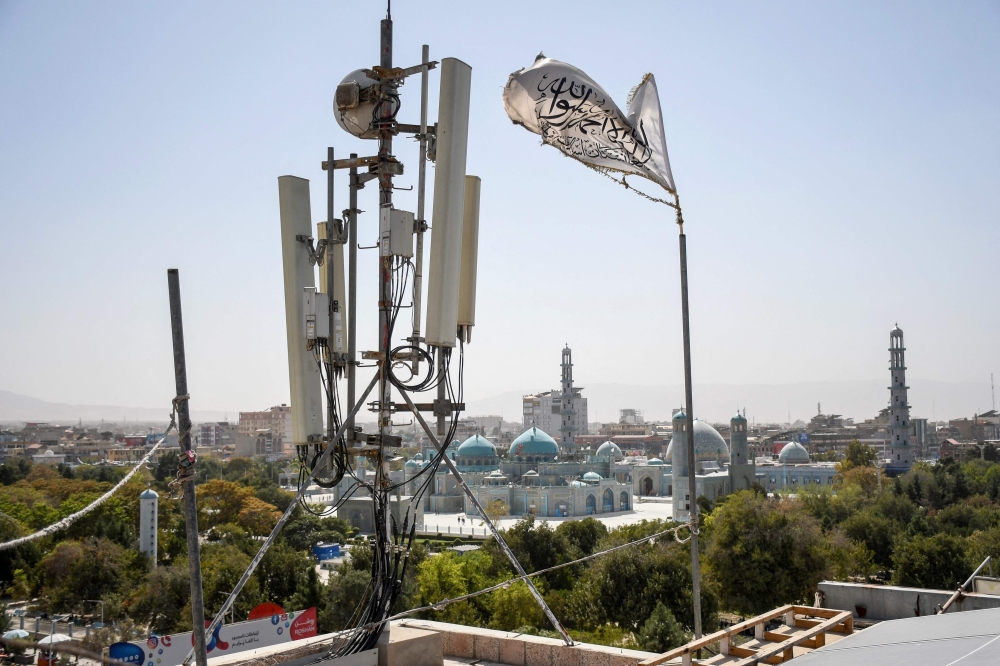 A Taliban flag flutters near telecom equipment installed over a rooftop providing internet services overlooking Hazrat-e-Ali Shrine, or Blue Mosque, in Mazar-i-Sharif on September 16, 2025, as the Taliban administration banned fibre-optic internet in Balkh province. — AFP pic