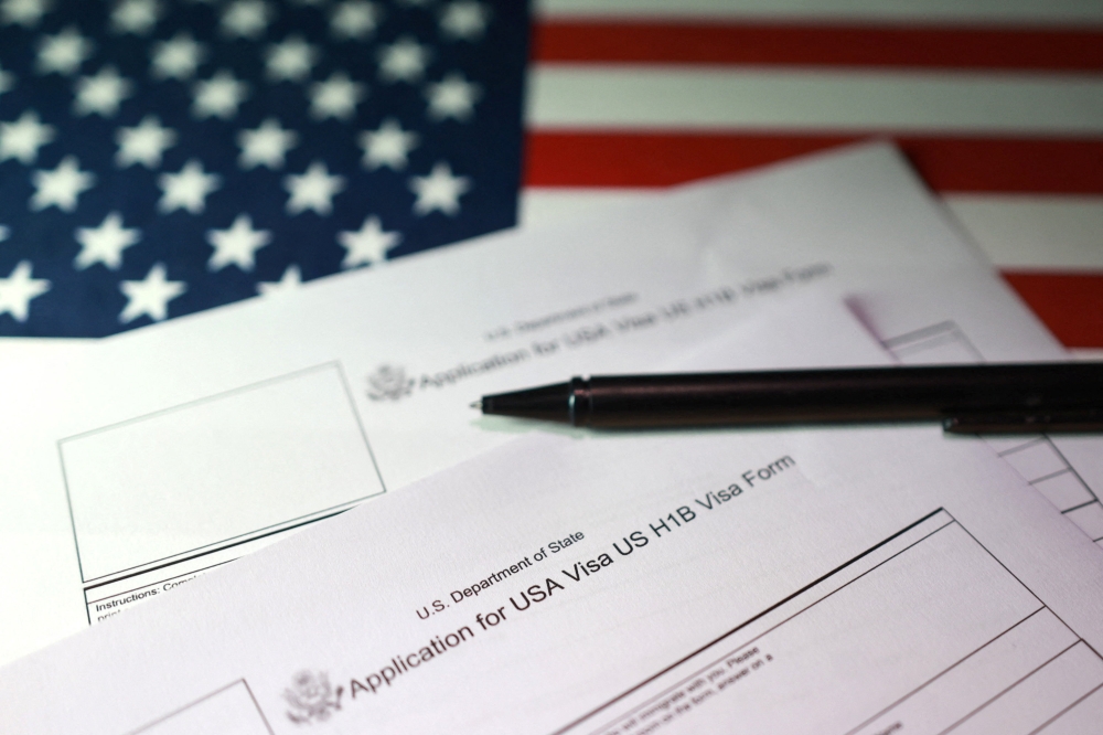 A US flag and US H-1B Visa application forms are seen in this illustration taken, September 22, 2025. — Reuters pic
