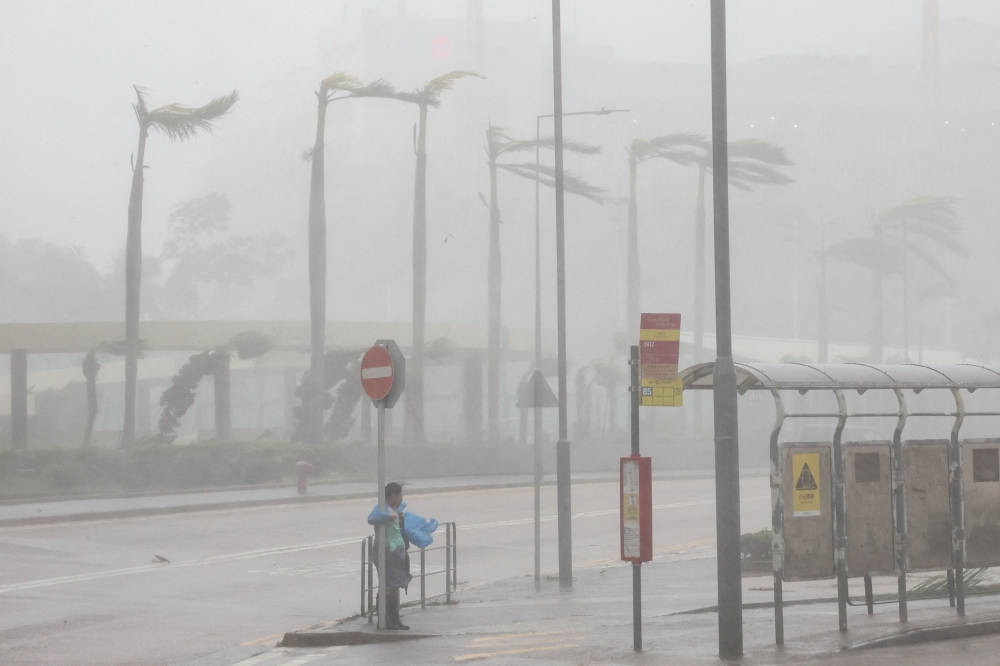 A woman clings to a traffic sign to maintain balance against strong winds from Super Typhoon Ragasa in Hong Kong, China, September 24, 2025. — Reuters pic 