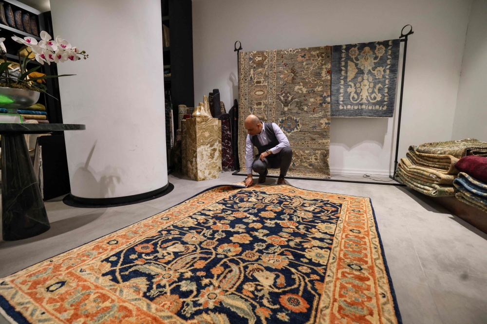 An Iranian man checks a rug at a shop selling antique and expensive carpets in northern Tehran on September 9, 2025. Once a symbol of unmatched artistry and cultural prestige, Iran’s handmade rugs are being unwoven from the global tapestry due to international sanctions and domestic pressures. — AFP pic 