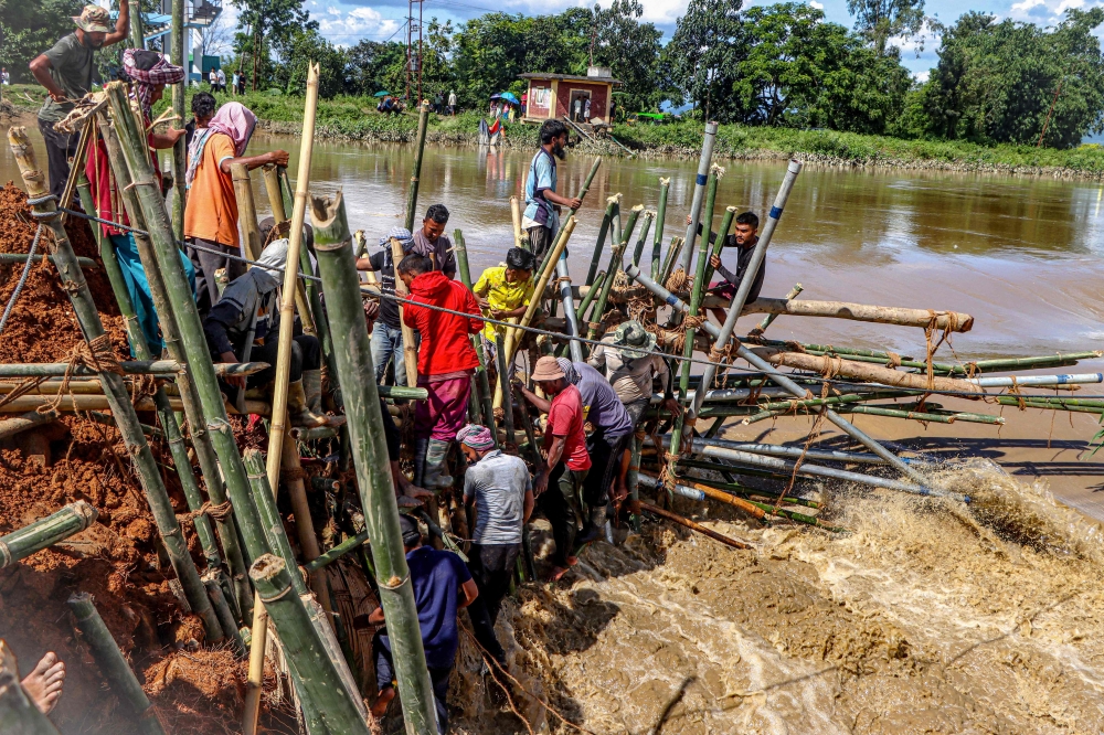 Local residents construct a temporary barrier using bamboo and poles to block a breach along the riverbank after heavy monsoon rains in Wangoi, Imphal West in India's northeastern state of Manipur September 17, 2025. At least 12 people died as heavy rain lashed the eastern Indian city of Kolkata and surrounding areas. — Reuters pic