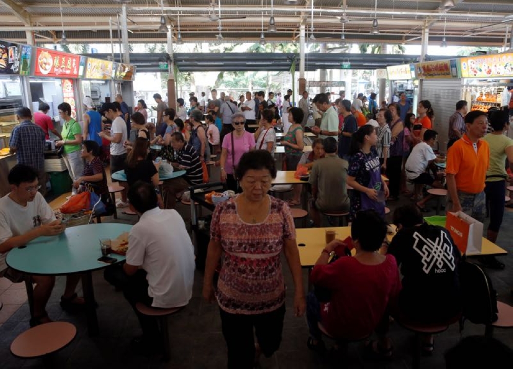 People queue for food at a hawker centre in Singapore in this file photo. Food establishments in Singapore will begin displaying a new halal certificate featuring a QR code from October 1. — Reuters pic