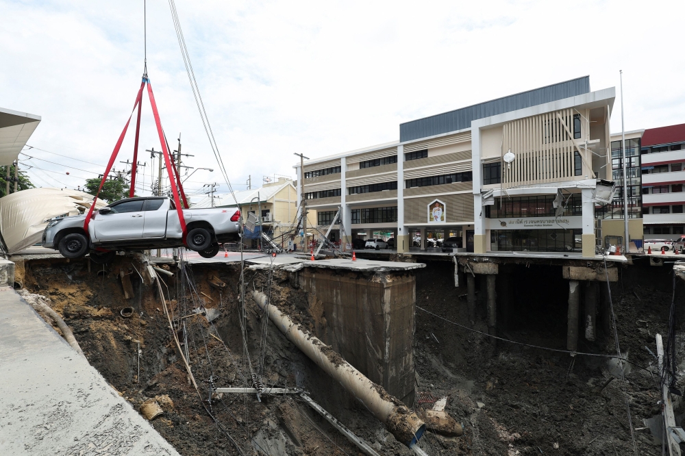 A vehicle teetering on the edge of a massive sinkhole that opened on Samsen Road near Vajira Hospital, is moved to a safe space, in Bangkok, September 24, 2025. — Reuters pic 