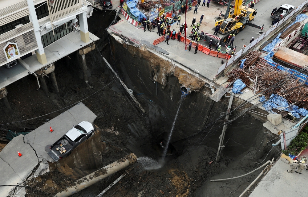 A vehicle teeters on the edge of a massive sinkhole that opened on Samsen Road near Vajira Hospital, in Bangkok, September 24, 2025. Teams in Bangkok are racing to fill a vast sinkhole on Samsen Road with sandbags and crushed stone to prevent further subsidence and the potential collapse of nearby structures. — Reuters pic 