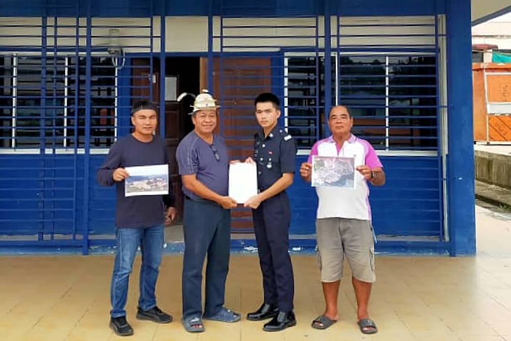 Tanah Adat & Lepuun Hulu Balui committee secretary Denis Hang Biland (2nd left) holds a copy of the police report at the Belaga post, while other committee members show photos of the affected area. — The Borneo Post pic
