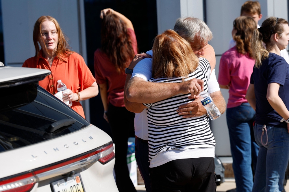 People hug near the reunification area outside of the NCG Cinema - Grand Blanc Trillium near the scene of a shooting at a church in Grand Blanc, Michigan, on September 28, 2025. — AFP pic