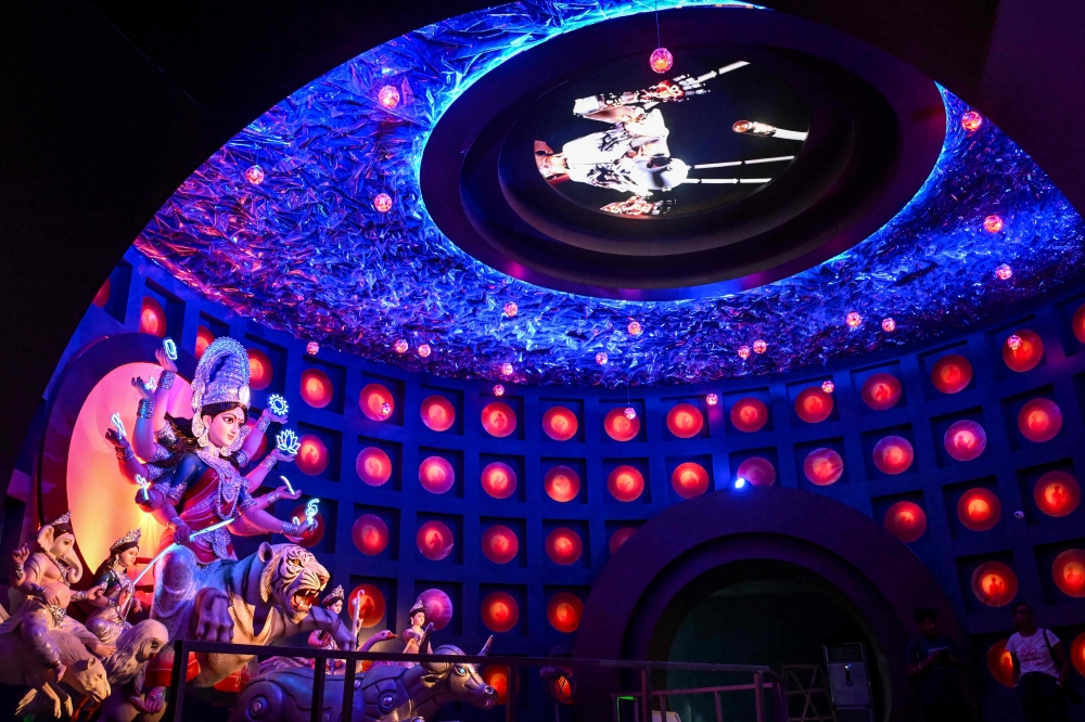 Visitors stand inside a 'Pandal' (temporary place for worship) next to an idol of the Hindu Goddess Durga, decorated with the theme of Artificial Intelligence (AI), in Kolkata on September 24, 2025, ahead of the Durga Puja festival. — AFP pic 