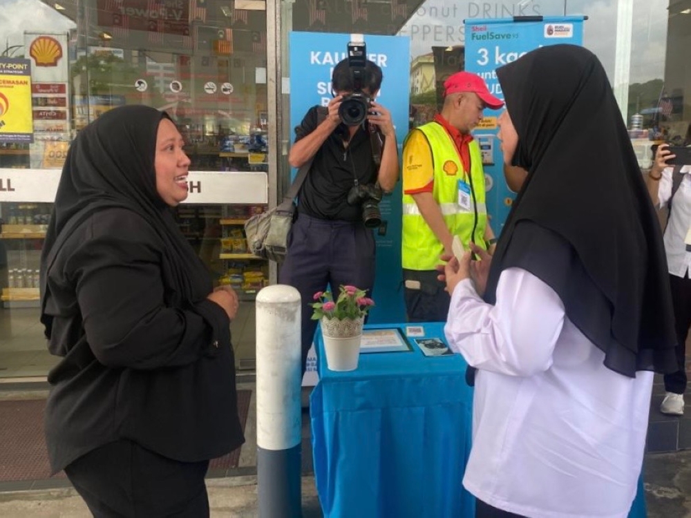 Johor Domestic Trade and Cost of Living Ministry (KPDN) director Lilis Saslinda Pornoma explains the Budi Madani RON95 (BUDI95) subsidy process to a customer at a petrol station in Johor Bahru on September 30, 2025. — Picture by Ben Tan
