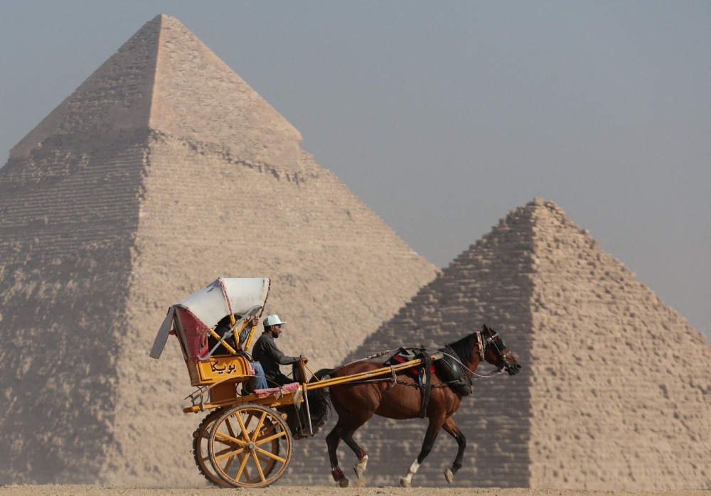 Tourists ride a horse-drawn cart in front of the Great Pyramids plateau in Giza, Egypt December 11, 2022. — Reuters pic