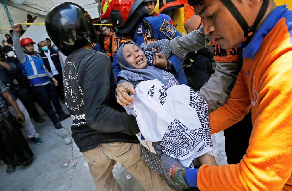 Members of the search and rescue operations carry a relative of the victim of a collapsed building, after a hall collapsed while students were praying at the Al-Khoziny Islamic boarding school on Monday, in Sidoarjo, East Java province, Indonesia, October 1, 2025. — Reuters pic