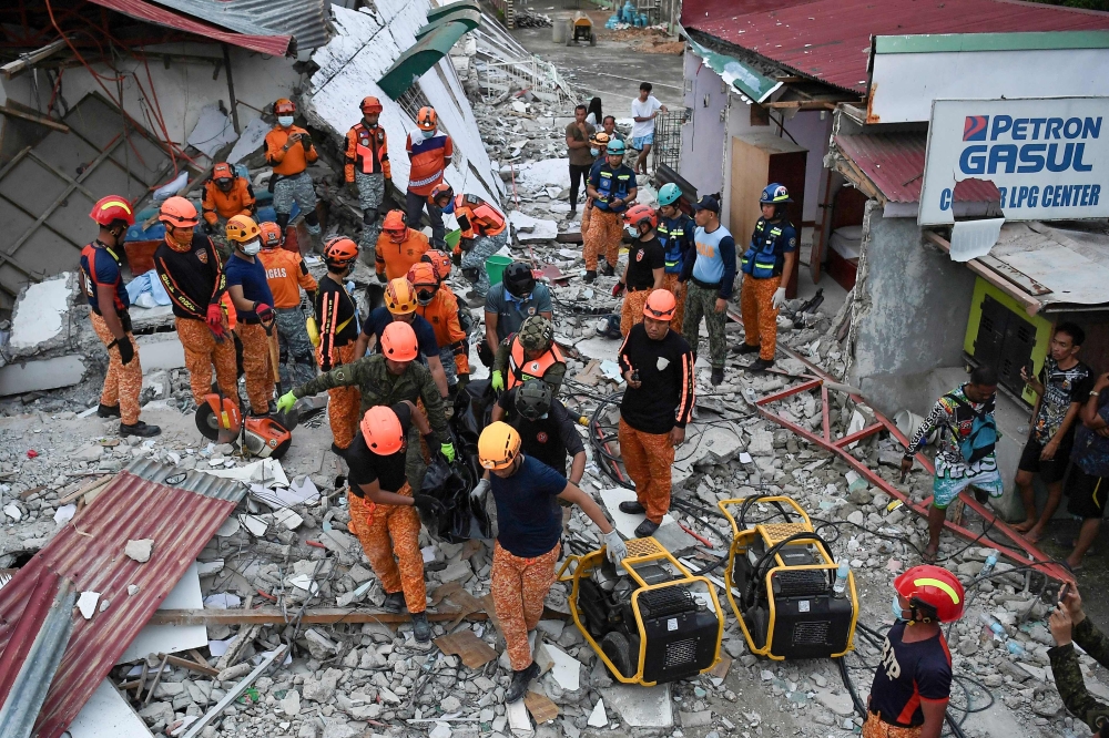 Rescuers carry a body bag containing a victim retrieved from the rubble of a collapsed building in Bogo City on October 1, 2025, after a 6.9-magnitude quake struck off the coast of the central Philippines late on September 30. — AFP pic