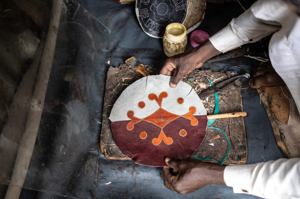 Yahaya Tijjani, a leather artisan, fixes a piece of leather on a fan in his workshop at the Kurmi market in Kano, on September 10, 2025. — AFP pic