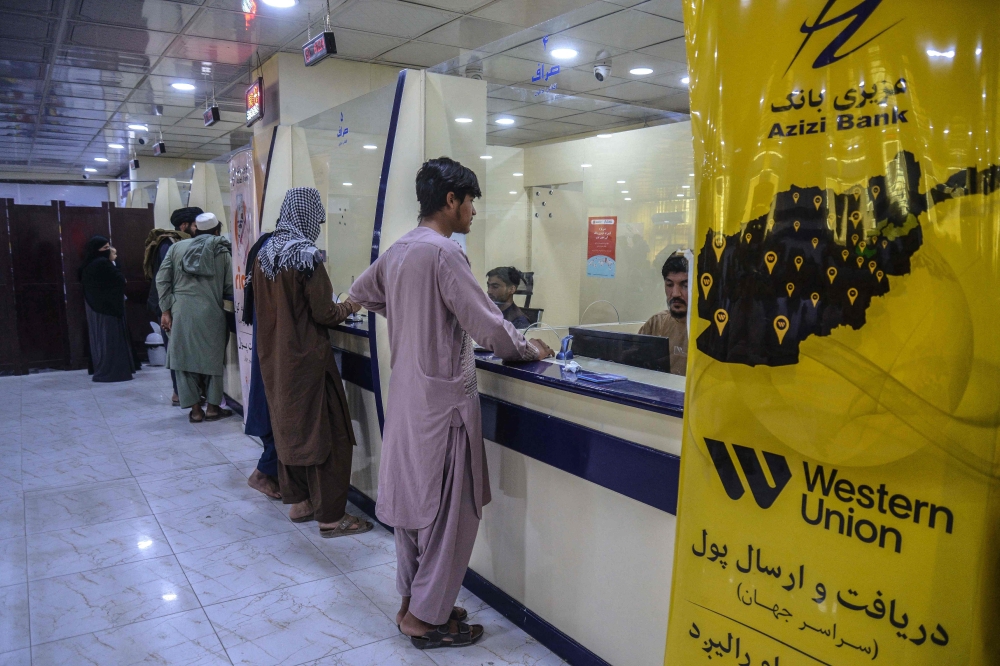 Afghan men wait inside a bank in Kandahar on October 2, 2025. — AFP pic