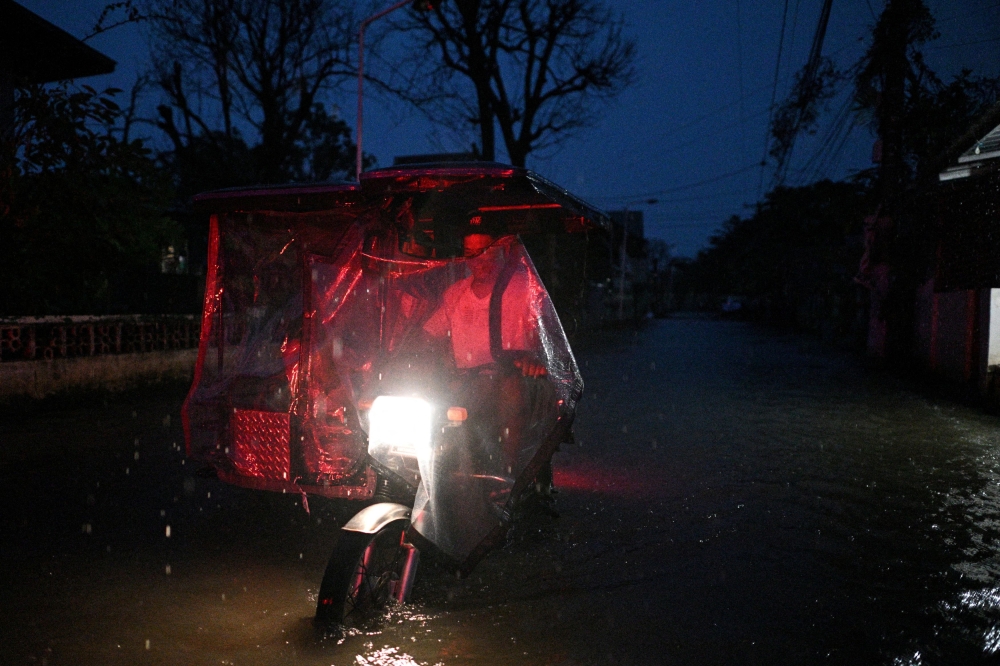 A man drives a tricycle through flooded street following rain, intensified by Severe Tropical Storm Matmo, in Santa Lucia, Calumpit, Bulacan province, Philippines, October 3, 2025. Chinese authorities will cancel flights and ferries in Hainan tonight before Typhoon Matmo hits the southern province. — Reuters pic