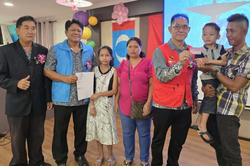 Tiang (third right) and Lee (second left) pose with Augustine, Rovina and their parents in an undated photocall. — The Borneo Post pic