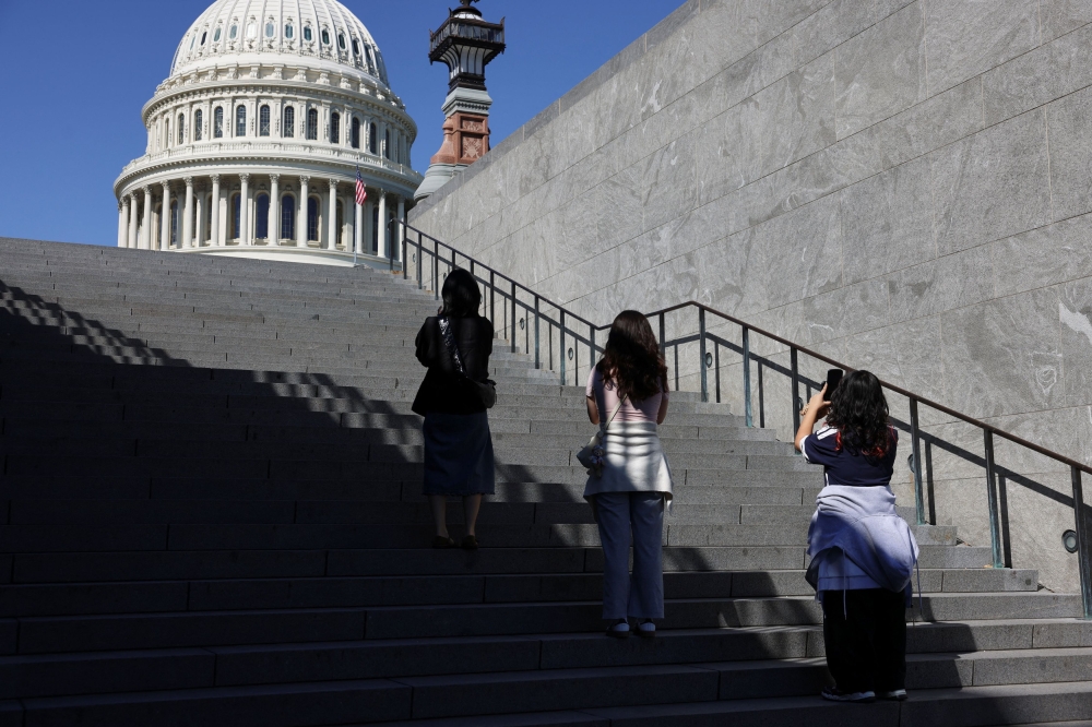 Tourists pause to take photos of the U.S. Capitol, which is closed to public tours, during the fourth day of a partial government shutdown in Washington, D.C. October 4, 2025. — Reuters pic