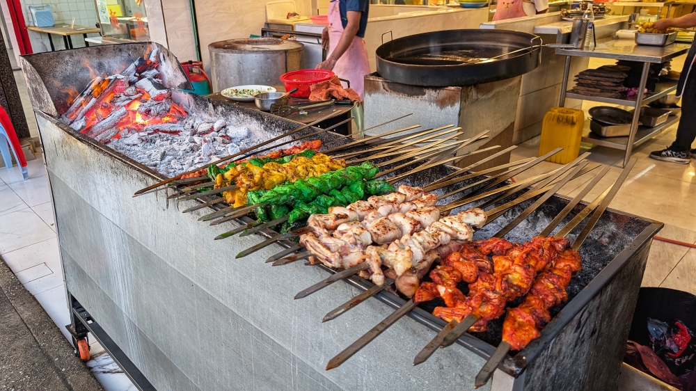 Outside the restaurant, skewers of ‘boti’ wait to be grilled over charcoal.  — Picture by Ethan Lau