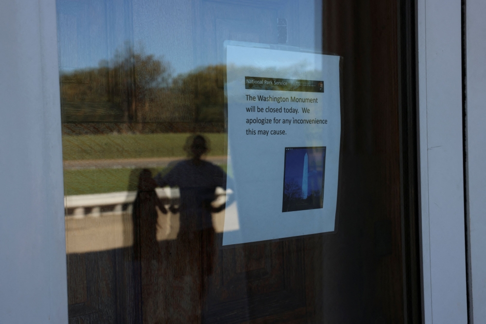 People stand outside of the Washington Monument as a sign announces it is closed, on the fourth day of a partial government shutdown in Washington, D.C. October 4, 2025. — Reuters pic