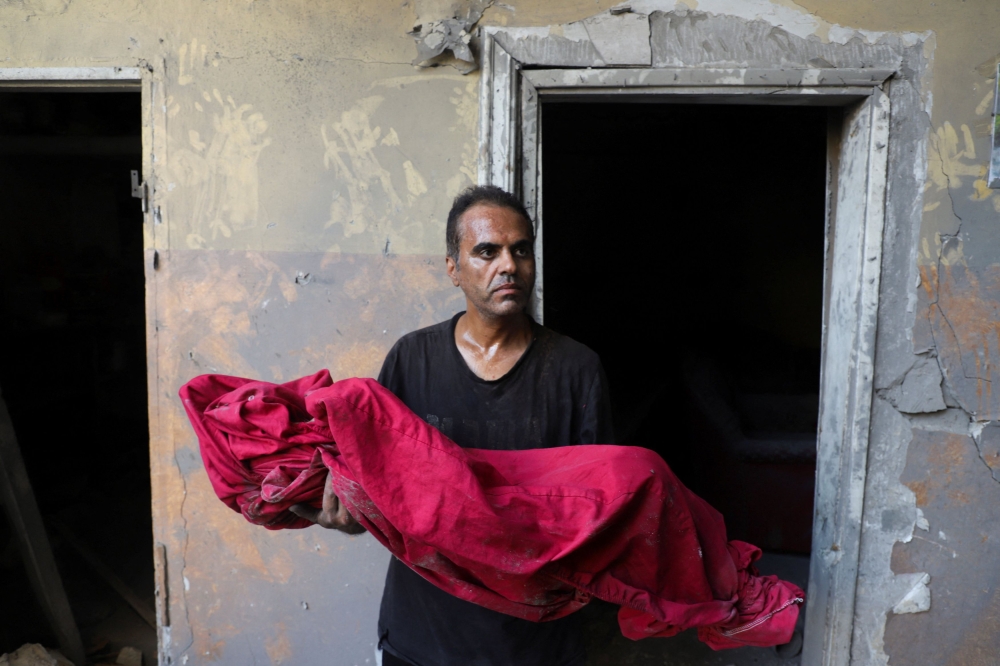 Palestinian father Shadi Mansour carries the body of his son Ameer, who was killed in an Israeli strike on Saturday on a house in the Tuffah neighborhood in Gaza City, October 5, 2025. — Reuters pic