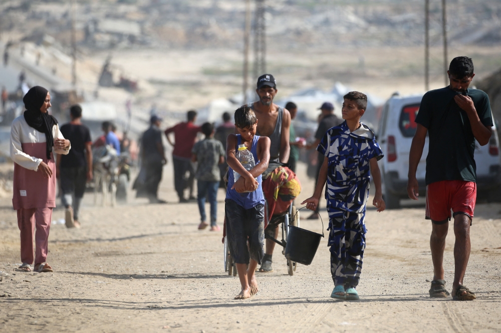 Palestinians walk on a coastal path northwest of Nuseirat refugee camp as they are displaced southward following an Israeli announcement of closing Al-Rashid road towards the north of the besieged Gaza Strip on October 4, 2025. — AFP pic