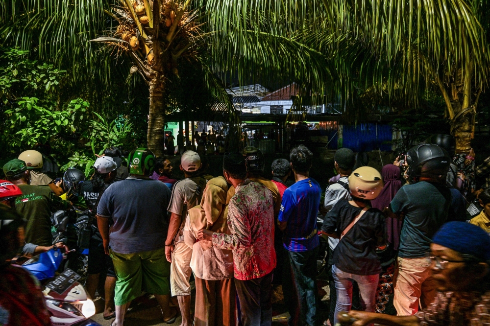 People gather to watch as a rescue operation is underway at the site of a collapsed building in a cordoned-off area at the Al Khoziny Islamic boarding school in Sidoarjo, East Java province, on October 2, 2025, after a multi-storey building at the school collapsed. — AFP pic
