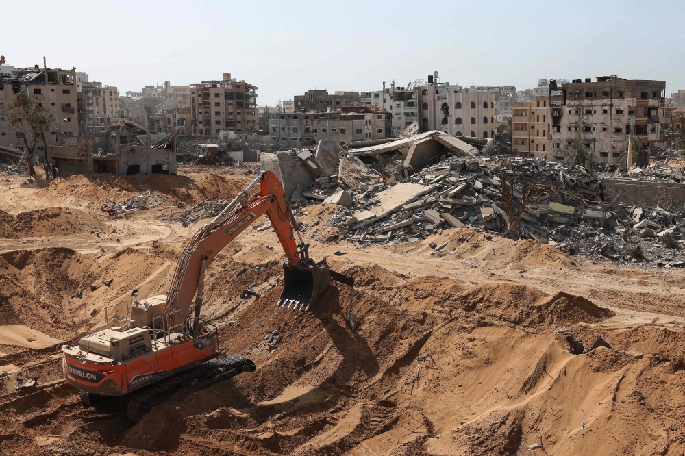 This picture taken during a media tour organised by the Israeli army on October 3, 2025, shows an excavator digging the soil in front of war-destroyed or damaged buildings in the vicinity of the Jordanian Field Hospital in Gaza City. — AFP pic 
