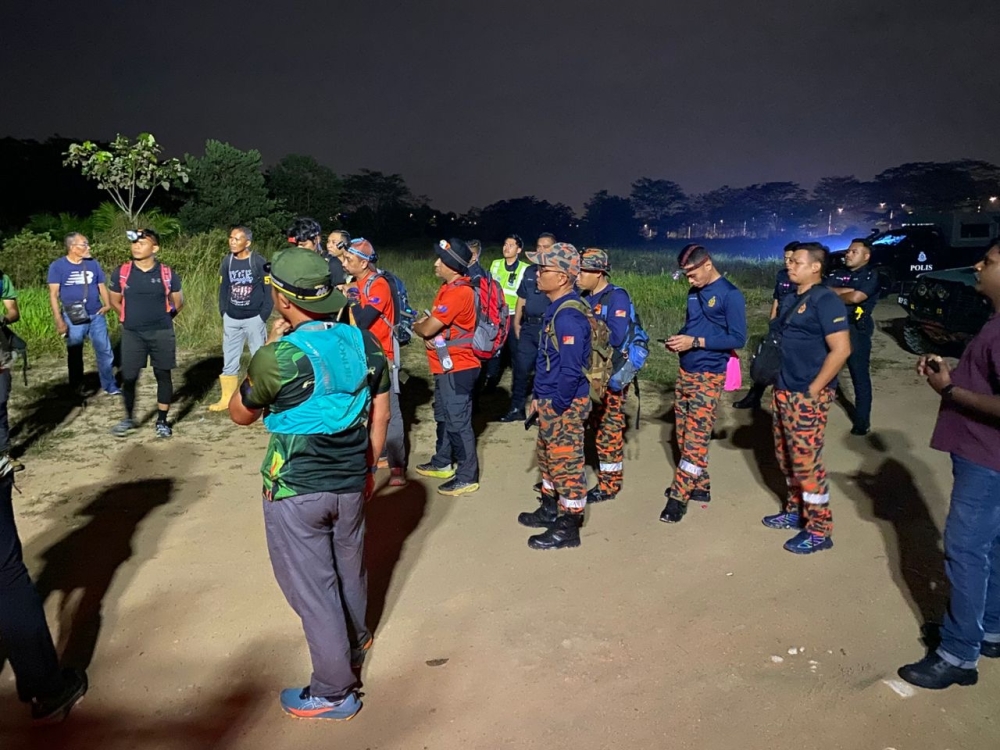 Firefighters and volunteers search for a man feared to have drowned after his boat capsized off Kampung Tebing Runtoh in Iskandar Puteri today. — Picture courtesy of the Johor Fire and Rescue Department