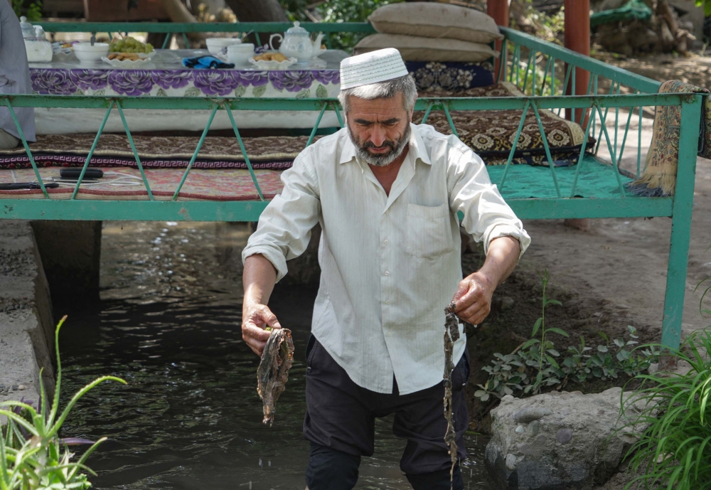 Tajik labourer Nematoullo Bassirov shows garbage he scooped from the stream running through his yard in the village in the Balkh district, known widely by its Soviet-era name of Kolkhozobod. — AFP pic