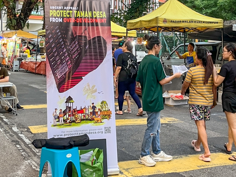A volunteer distributing Protect Taman Desa flyers to visitors of Taman Desa's Friday night market. — Picture courtesy of Protect Taman Desa