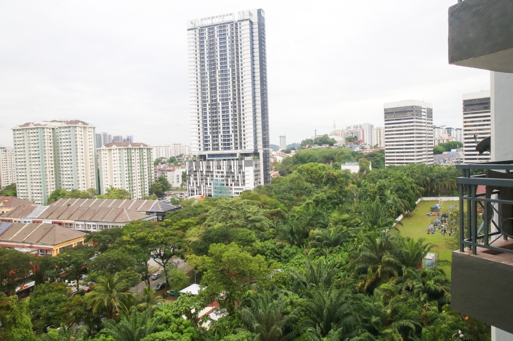 The playground land covered with trees is a precious green lung in Taman Danau Desa. As a rough visual guide, the rectangular land stretches from the white tent at the photo’s lower portion, up to the white-water tank at the photo’s upper part. On its right is a secondary school, while opposite it (on its left) is the tallest building in the photo, Kensho Residence. — Picture by Choo Choy May
