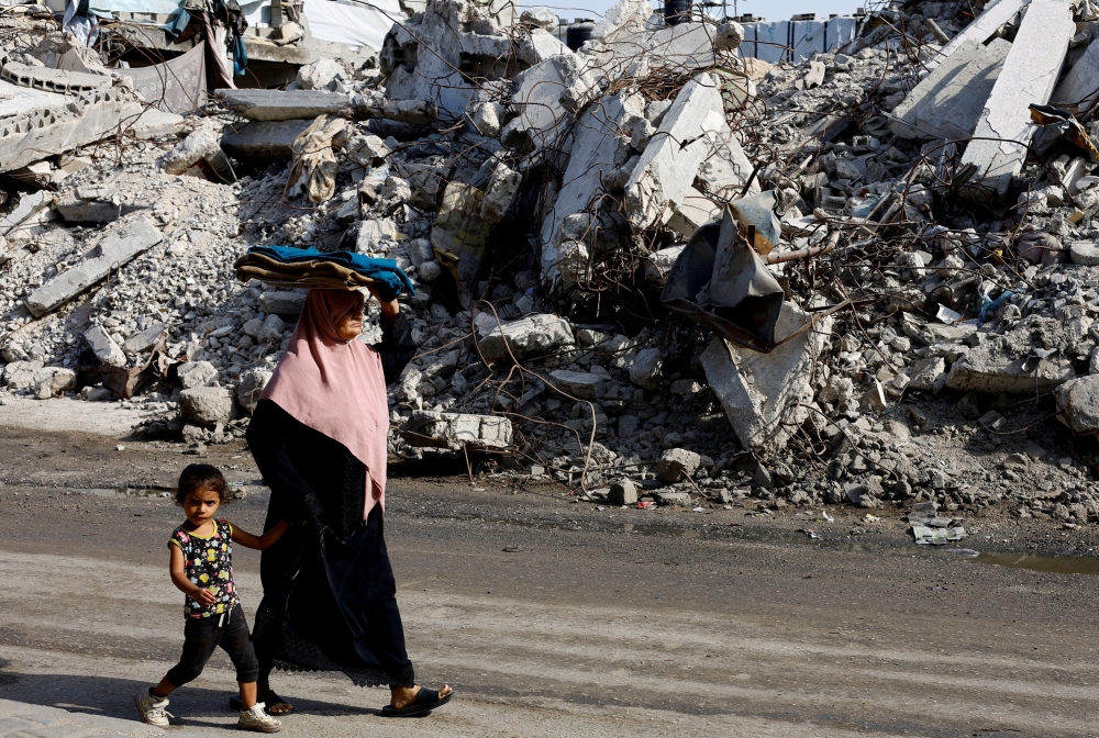 Palestinians walk past a residential building destroyed in previous Israeli strikes, after Hamas agreed to release hostages and accept some other terms in a US plan to end the war, in Nuseirat, central Gaza Strip October 4, 2025. — Reuters pic  