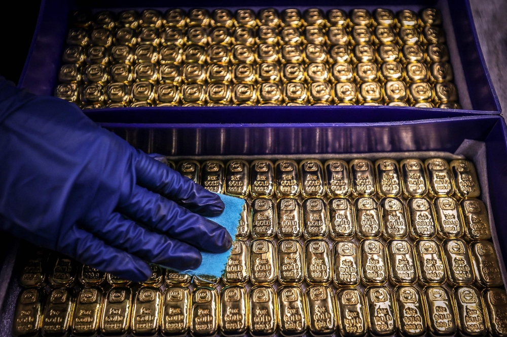 A worker polishes gold bullion bars at the ABC Refinery in Sydney on August 5, 2020. — AFP pic