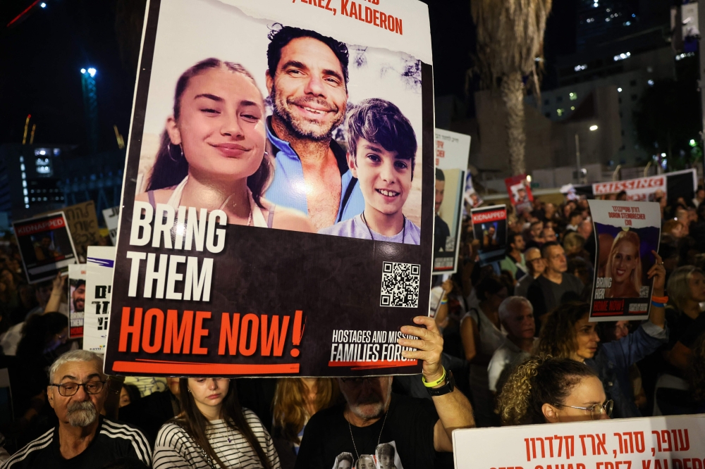 ChatGPT said:Protesters hold placards during a rally in Tel Aviv on November 18, 2023, demanding the release of Israelis held hostage in Gaza following Hamas’s October 7 attacks. — AFP pic