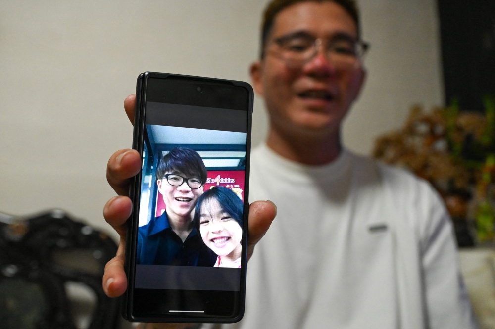 This photograph taken on September 18, 2025 shows Singapore’s Delfard Tay showing a photo with his late daughter Shermaine, in Singapore. Since losing his only daughter in a fall from their high-rise flat in Singapore, Delfard Tay has turned grief into purpose, sounding the alarm on drug-laced vapes that put teenagers’ lives at risk. — AFP pic