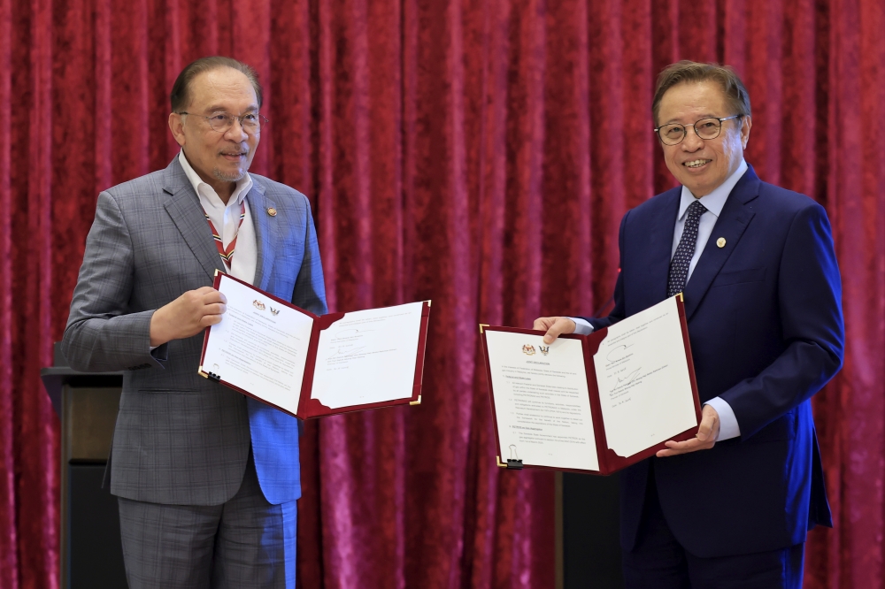 Prime Minister Datuk Seri Anwar Ibrahim exchanges a memorandum of understanding with Sarawak Premier Tan Sri Abang Johari Tun Openg during the Memorandum of Understanding Exchange Ceremony in Putrajaya today. — Bernama pic