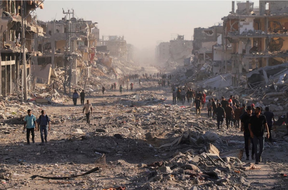 Palestinians walk through a damaged neighbourhood in Gaza City in the aftermath of an Israeli operation. — Reuters pic