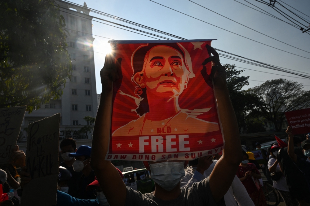 A protester holds up a poster featuring Aung San Suu Kyi during a demonstration against the military coup at in front of the Central Bank of Myanmar in Yangon on February 15, 2021. — AFP pic