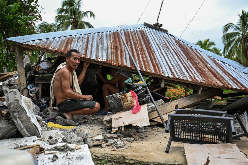 Men search for belongings inside a collapsed house in Manay, Davao Oriental, on October 11, 2025, a day after two powerful offshore earthquakes struck the southern Philippines and killed at least eight people. — AFP pic