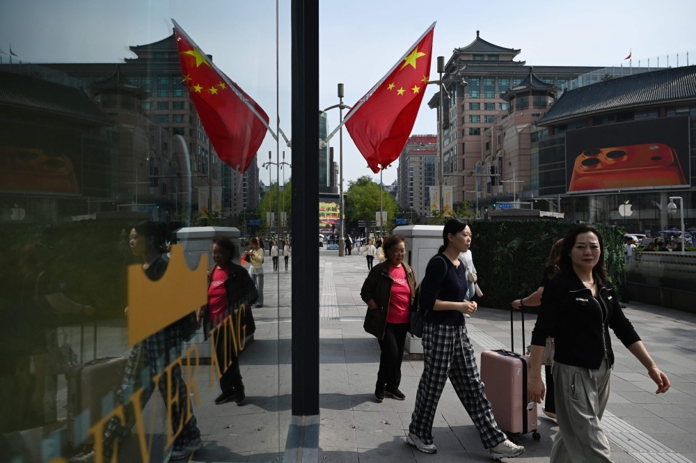 People walk outside a shopping mall during a week-long National Day holiday in Beijing on October 7, 2025. Residents of China’s capital city expressed indifference and defiance today when asked by AFP about the latest threat by US President Donald Trump to impose blistering new tariffs on the country. — AFP pic