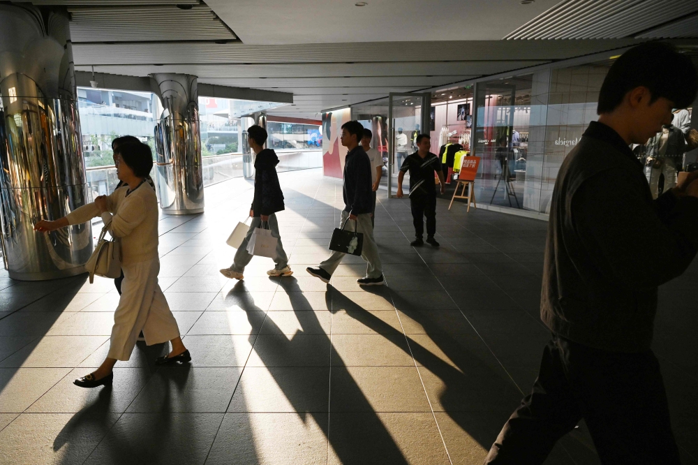 People walk through a shopping mall during a week-long National Day holiday in Beijing on October 7, 2025. — AFP pic