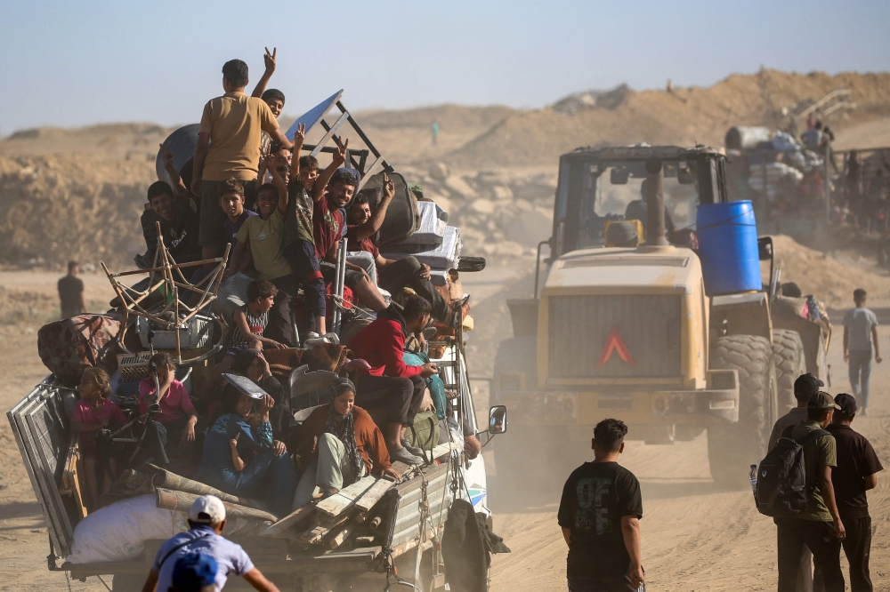 Palestinians flash the V-for-victory sign as they make their way to Gaza City through the so-called “Netzarim corridor” from Nuseirat in central Gaza on Oct 11, 2025. Israel declared a ceasefire in Gaza and began pulling back its forces on Oct 10, as tens of thousands of exhausted Palestinians returned to their devastated homes. — AFP pic