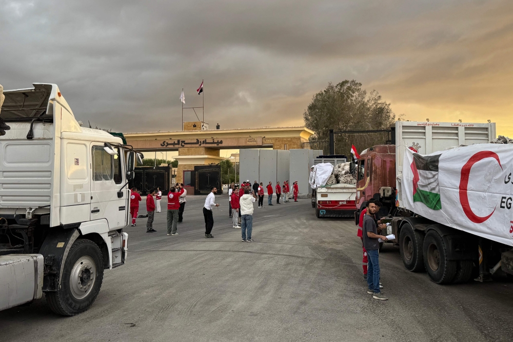Members of the Red Crescent stand near a trucks loaded with humanitarian aid on the Egyptian side of the Rafah crossing, waiting to get access to the Gaza Strip. — AFP pic