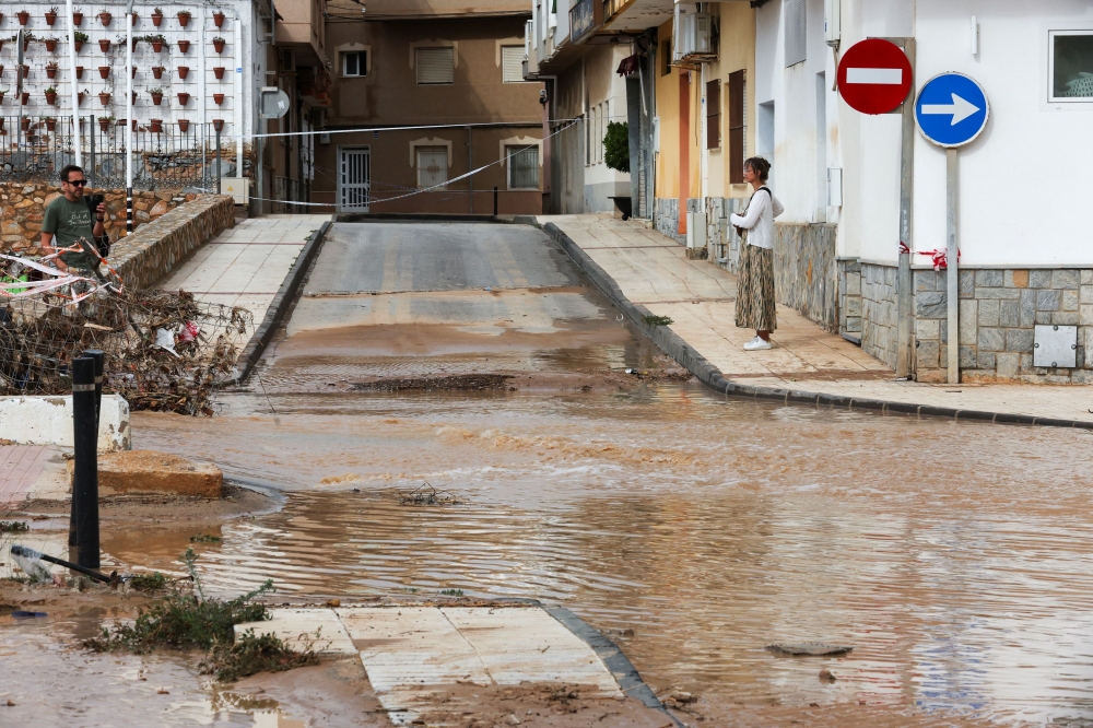 People stand next to a flooded road, after heavy rains in Los Alcazares, Murcia, Spain, October 11, 2025. — Reuters pic 