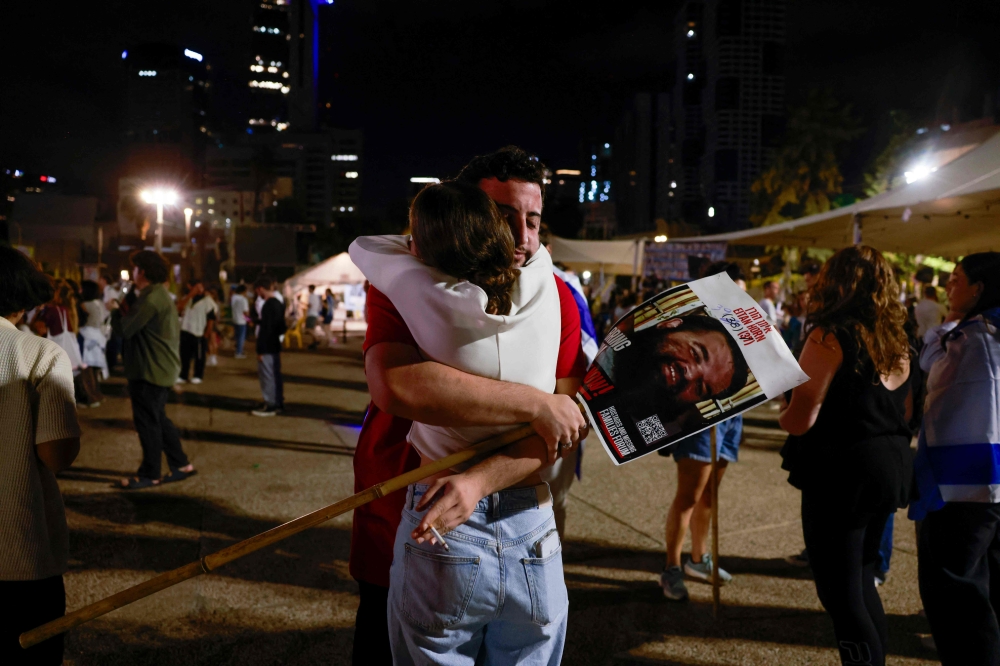 A man and a woman embrace at Hostage Square in Tel Aviv early on October 13, 2025. — AFP pic