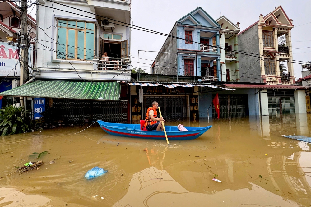 A man rows a canoe through waters past buildings in That Khe commune flooded after heavy rains caused by Typhoon Matmo in Lang Son province on October 8, 2025. — AFP pic 