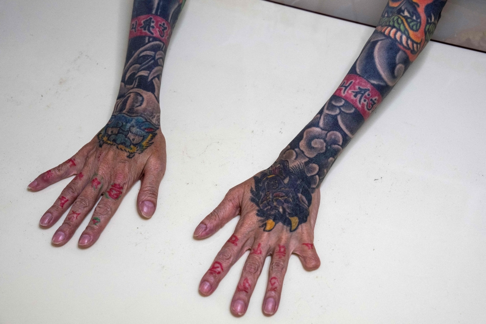In this photograph taken on September 28, 2025, retired yakuza Mako Nishimura shows her forearm heavily inked with dragon and tiger tattoos and a missing fingertip, that she cut off on her own as part of the yakuza's ritualistic self-punishment for blunders, during an interview with AFP at her residence in Gifu. — AFP pic