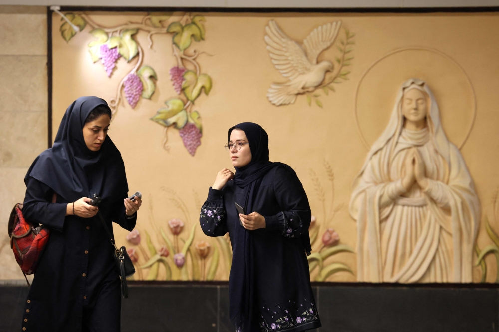 Iranian women walk past a relief of the Virgin Mary at the new Maryam Moghaddas metro station near Sarkis Cathedral in Tehran on October 18, 2025. — AFP pic