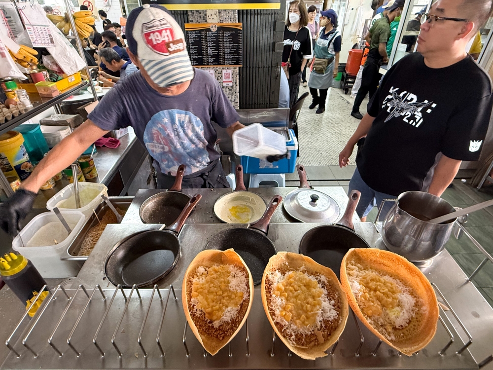 The counter is busy as the stall owner deftly manages the hot pans with the pancakes. — Picture by Lee Khang Yi