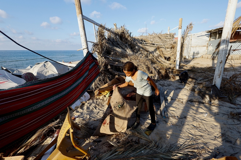 A Palestinian girl inspects the site of an Israeli airstrike on a cafe, according to the civil defense, in Deir al-Balah, central Gaza Strip October 19, 2025. — Reuters pic  